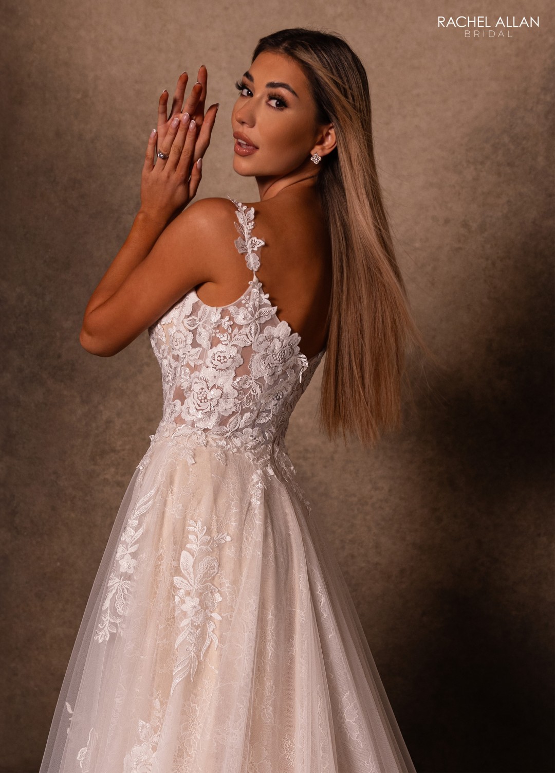 Ivory bridal gown with floral lace appliqués, illusion sleeves, and voluminous train