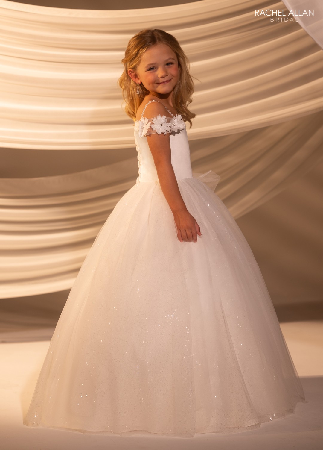 White flower girl dress with layered tulle skirt, lace bodice, and satin bow back