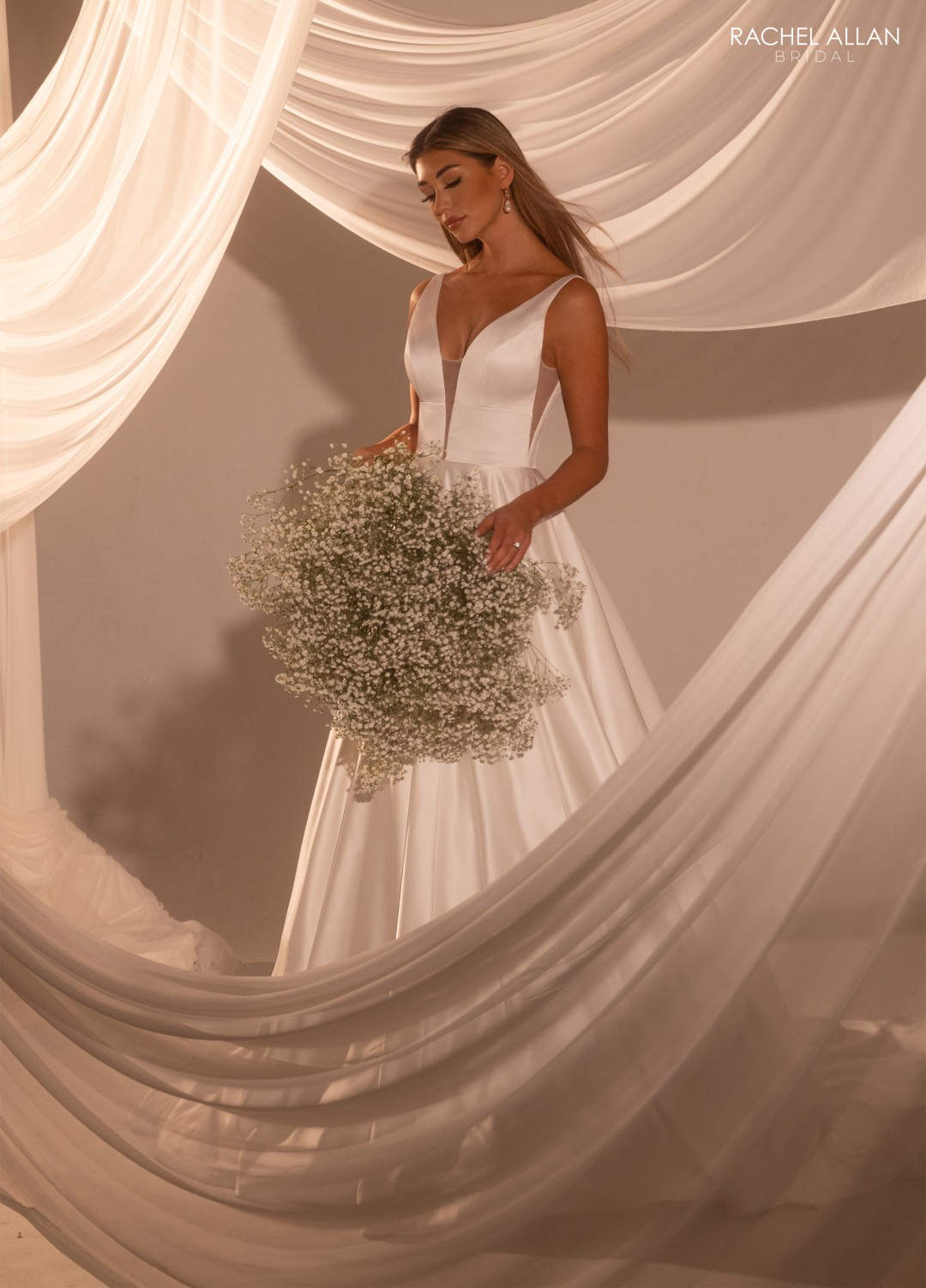 2.	Rachel Allan Style RB2222 V-neck A-line bridal dress in lustrous satin with plunging neckline and sweeping train with covered buttons
